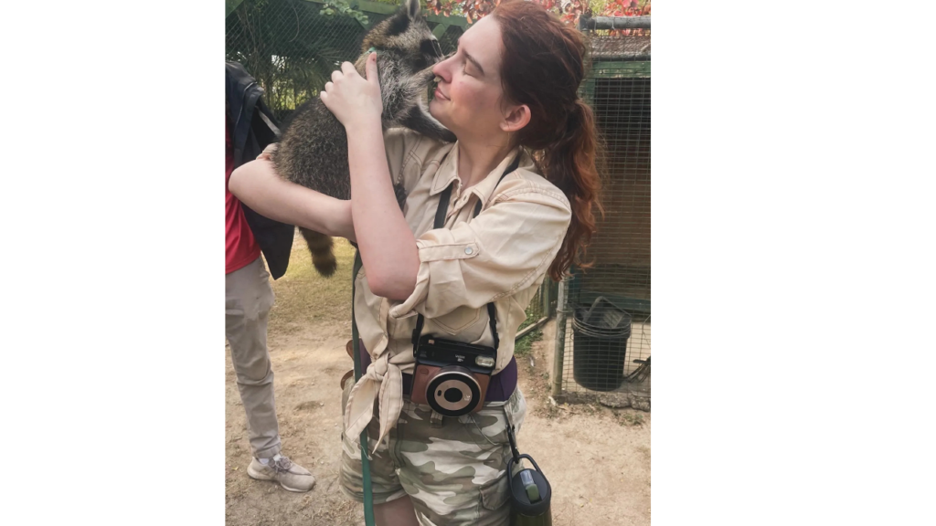 Lochlan O’Neil, a woman in her 20s, holding up a raccoon near her face